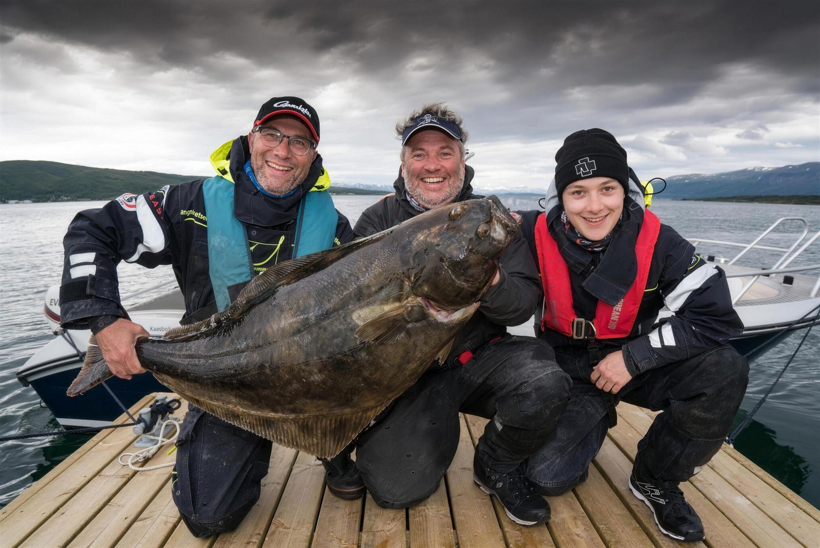 Three guests holding a large halibut on the Vikran pier